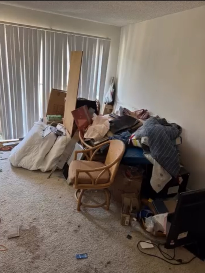 Apartment room crowded with furniture, boxes and household junk before cleanout