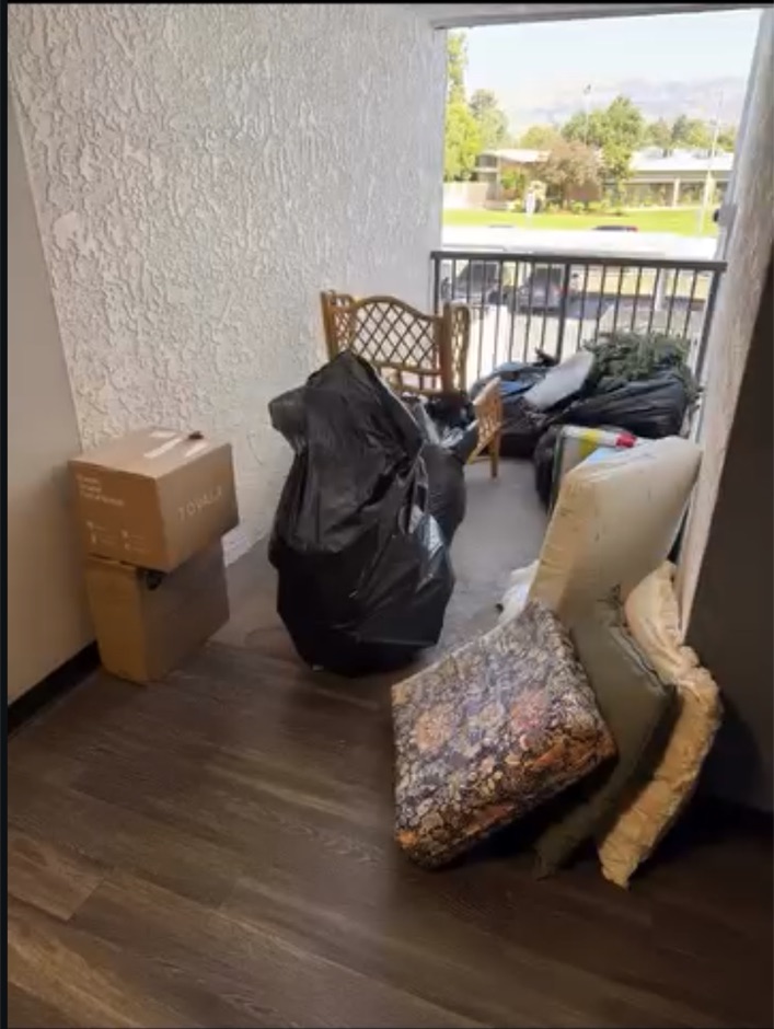 Apartment patio and doorway blocked by bags, cushions and furniture before cleanout