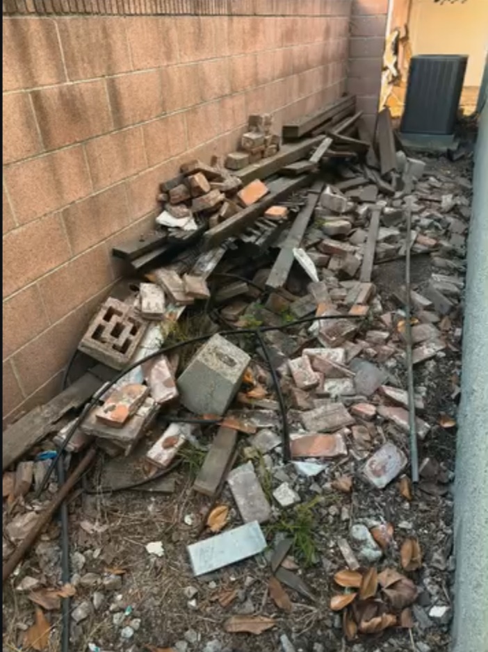 Side yard filled with broken masonry, lumber and debris before cleanup